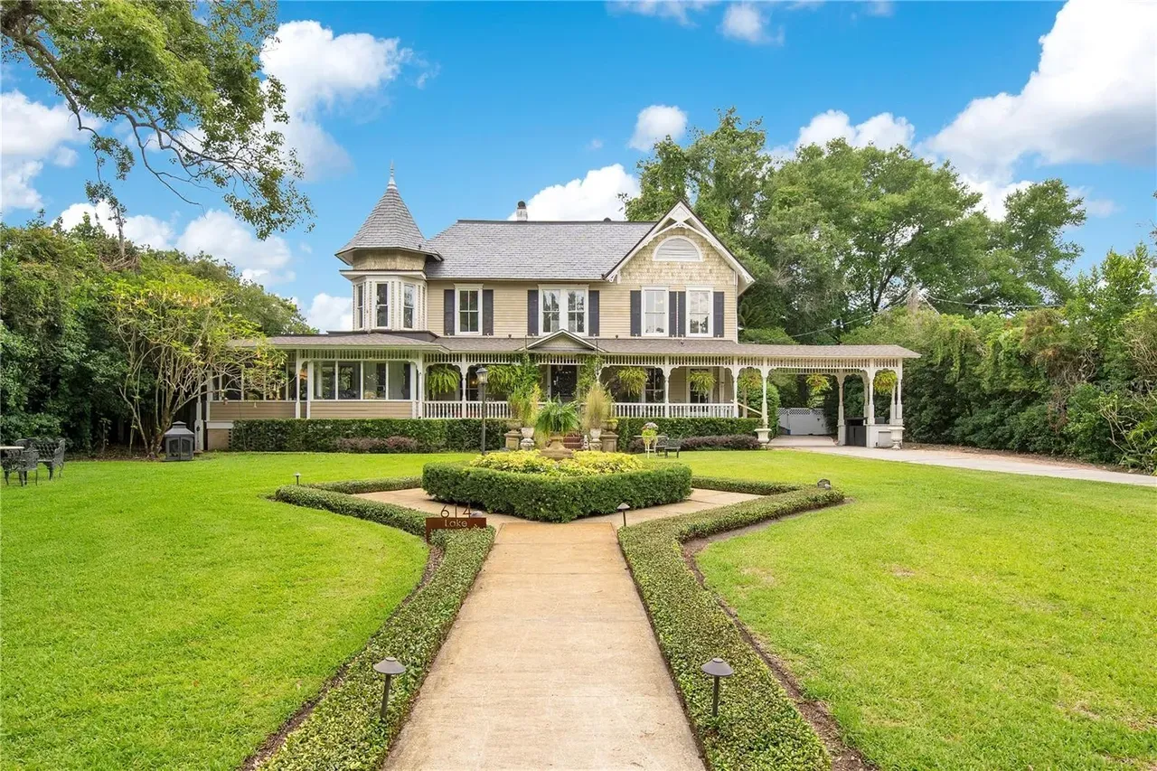 The Poyntz-O'Neal House at 614 South Lake — a large two-story Queen Anne residence with wraparound porch, white wood siding, and the live oaks of Lake Cherokee behind it